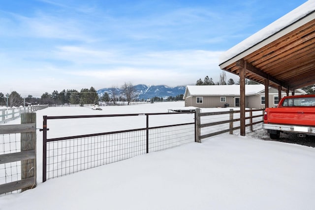 yard covered in snow with a carport, fence, and a mountain view