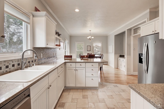 kitchen featuring appliances with stainless steel finishes, ornamental molding, white cabinets, a sink, and a peninsula