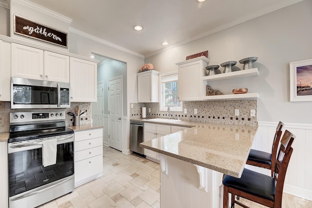 kitchen featuring stainless steel appliances, tasteful backsplash, a sink, a peninsula, and a kitchen breakfast bar