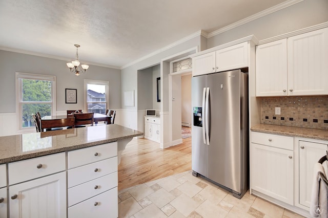 kitchen with white cabinets, stainless steel fridge with ice dispenser, light stone countertops, crown molding, and a notable chandelier