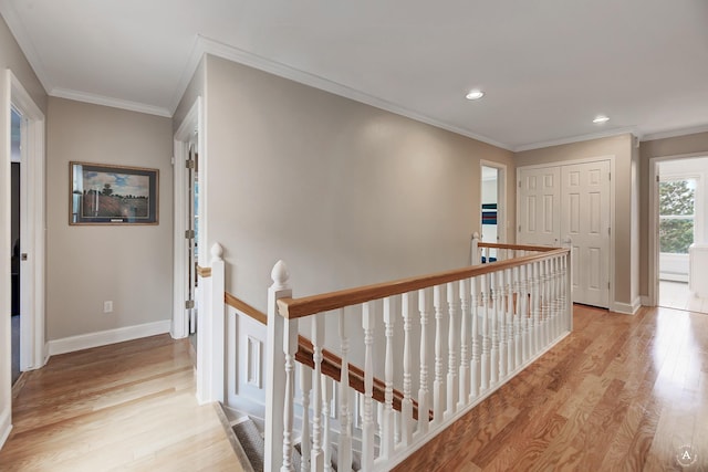 hall featuring light wood-style flooring, an upstairs landing, and baseboards