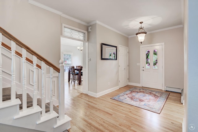 entrance foyer with stairs, crown molding, baseboard heating, and wood finished floors