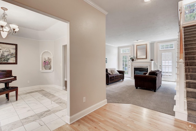 corridor featuring baseboards, stairway, a chandelier, and ornamental molding