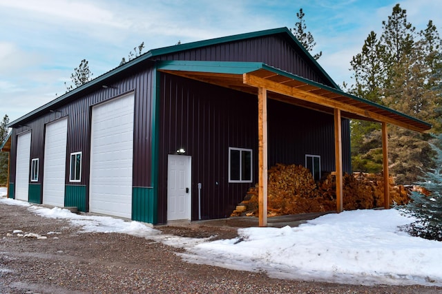 snow covered property with a detached garage and an outbuilding