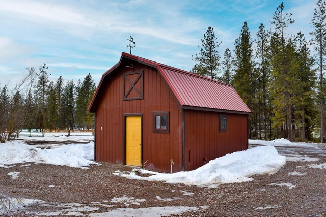 snow covered structure with a barn and an outbuilding