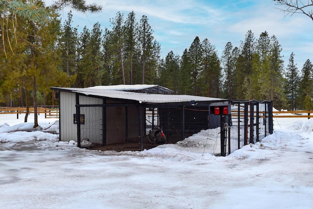 snow covered structure with fence and an outdoor structure