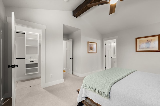 bedroom with a walk in closet, vaulted ceiling with beams, light carpet, ceiling fan, and baseboards