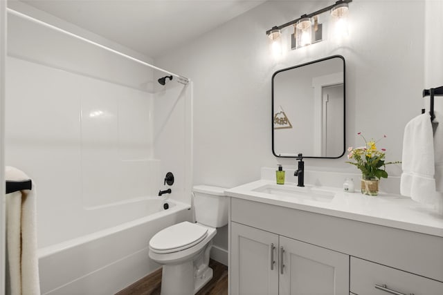 bathroom featuring toilet, washtub / shower combination, wood finished floors, and vanity