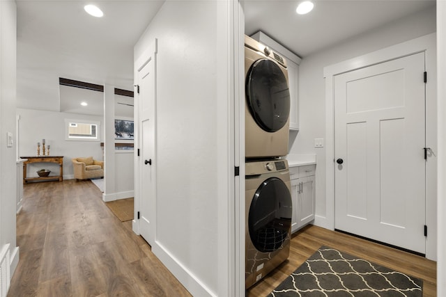 washroom featuring cabinet space, recessed lighting, stacked washer / drying machine, and wood finished floors