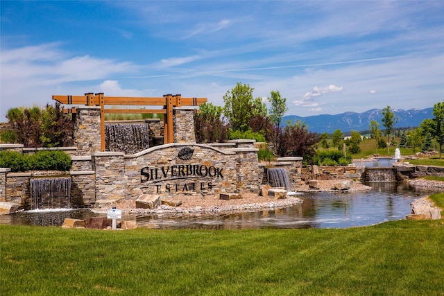 community / neighborhood sign with a yard and a mountain view