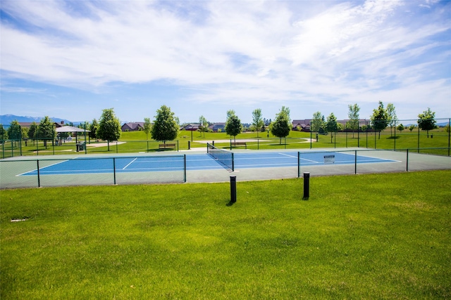 view of tennis court featuring a lawn and fence