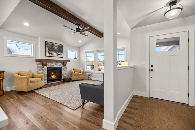 entryway with vaulted ceiling with beams, plenty of natural light, wood finished floors, and a stone fireplace