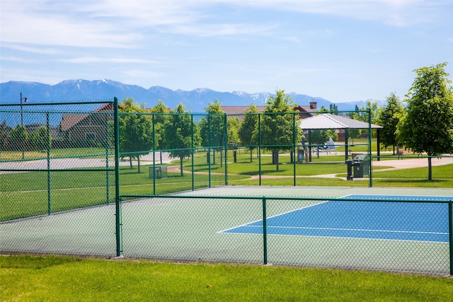 view of sport court with a lawn, fence, and a mountain view