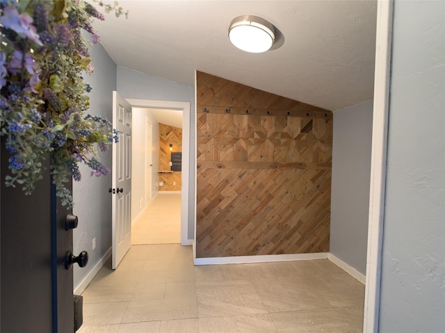 interior space with lofted ceiling, wood walls, and baseboards