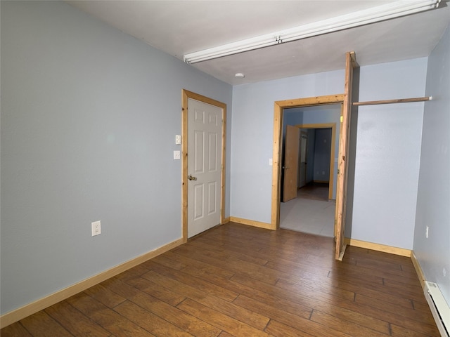 spare room featuring hardwood / wood-style flooring, baseboards, and a baseboard heating unit