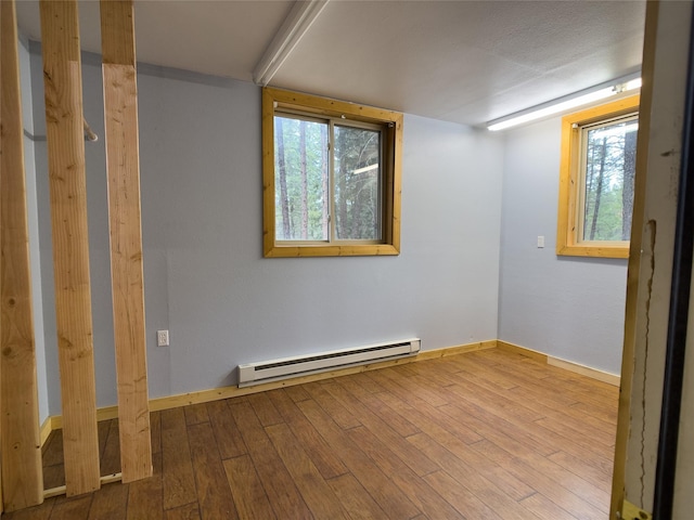 spare room with a baseboard radiator, hardwood / wood-style flooring, and baseboards