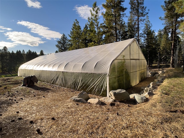 view of property exterior with a greenhouse and an outbuilding