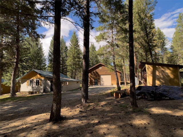 exterior space featuring an outbuilding, dirt driveway, and a detached garage