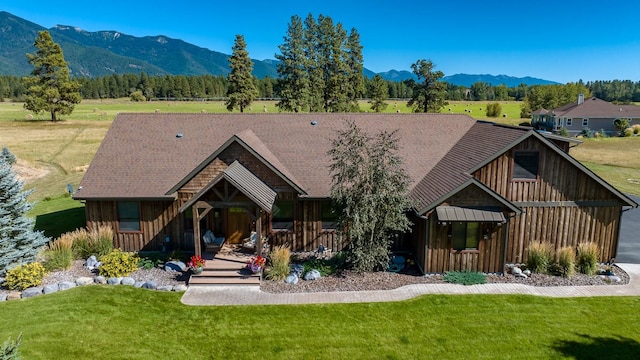 exterior space with board and batten siding, covered porch, a mountain view, and a front lawn