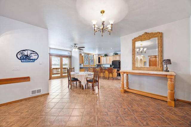 tiled dining area featuring ceiling fan with notable chandelier, visible vents, and baseboards