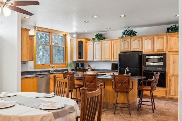 kitchen featuring a sink, a kitchen breakfast bar, a center island, black appliances, and dark countertops