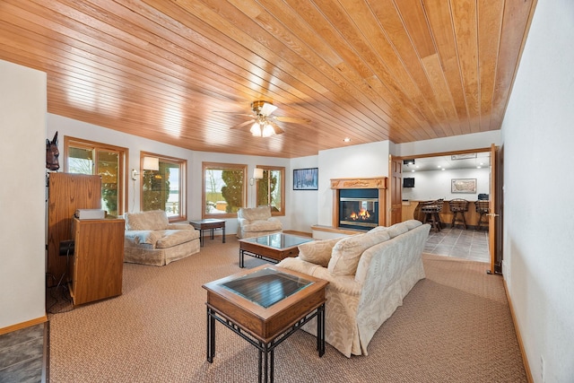 living room with carpet flooring, a glass covered fireplace, wooden ceiling, and baseboards