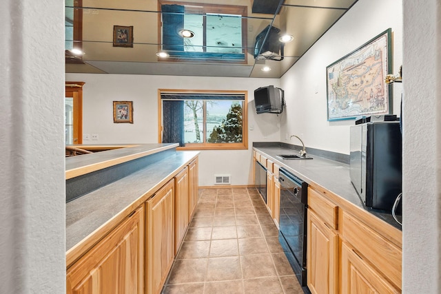 kitchen featuring light tile patterned flooring, light brown cabinets, a sink, visible vents, and dishwasher