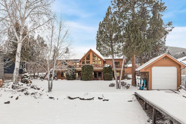 yard covered in snow featuring a garage, an outbuilding, and a deck