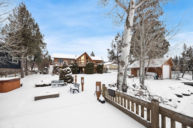 yard covered in snow with a garage, an outbuilding, and fence