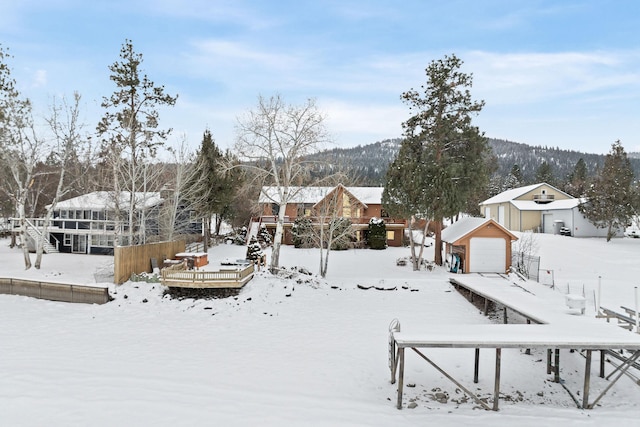 yard covered in snow with an outbuilding, fence, a garage, a wooden deck, and stairs