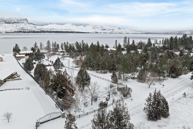 snowy aerial view featuring a water and mountain view