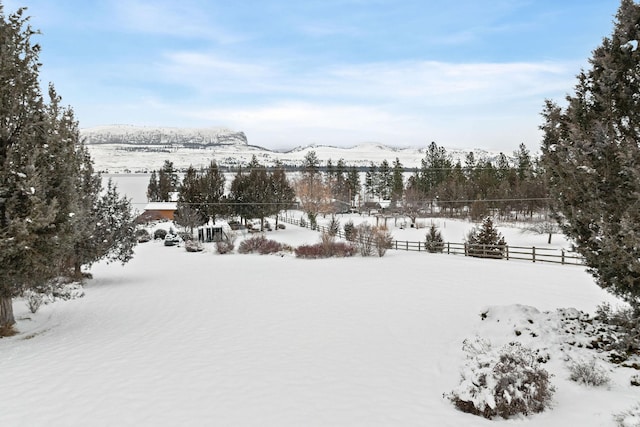 yard layered in snow with fence and a mountain view