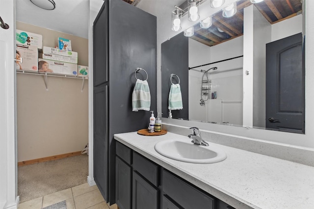 bathroom featuring a shower, vanity, baseboards, and tile patterned floors