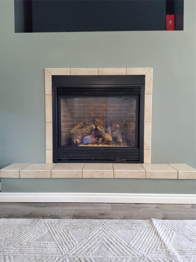 details featuring a tile fireplace and wood finished floors