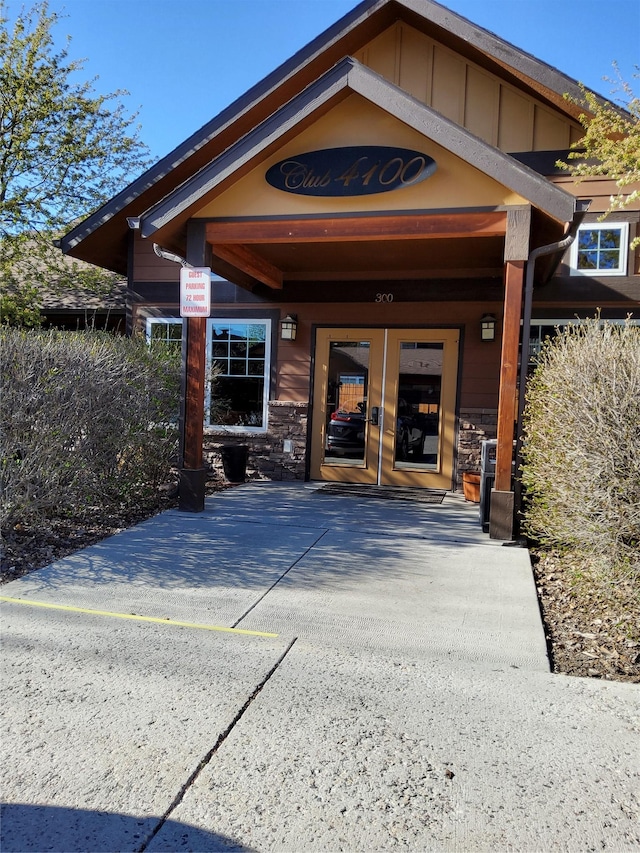 doorway to property with board and batten siding, french doors, and stone siding