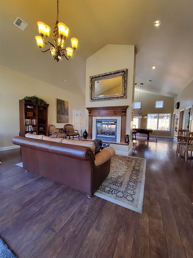 living area with dark wood-style floors, high vaulted ceiling, visible vents, a glass covered fireplace, and a chandelier