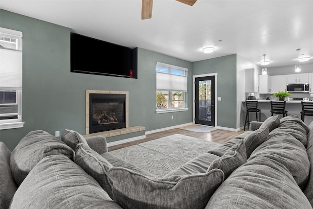 living room featuring light wood finished floors, a fireplace, and baseboards