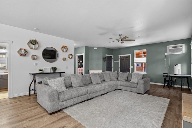 living area featuring plenty of natural light, baseboards, a ceiling fan, wood finished floors, and a wall mounted AC