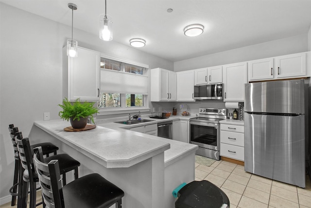 4100 Mullan Rd Unit 107, Missoula, MT 59808 - kitchen featuring appliances with stainless steel finishes, a peninsula, light countertops, white cabinets, and a kitchen breakfast bar