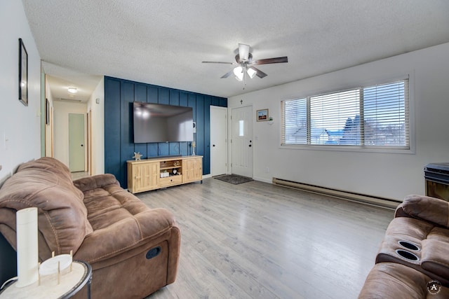 living room with a textured ceiling, wood finished floors, a ceiling fan, baseboards, and baseboard heating