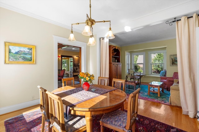 dining room with crown molding, baseboards, and wood finished floors