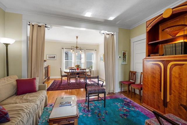 living area with ornamental molding, wood finished floors, and a notable chandelier