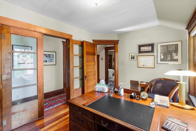 office area featuring lofted ceiling, a textured ceiling, baseboards, and wood finished floors