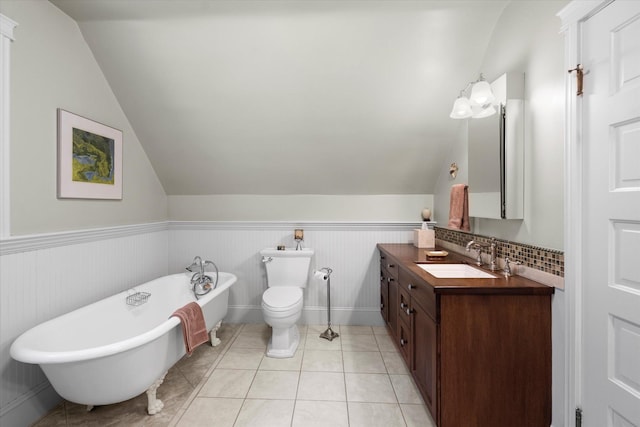 full bath with wainscoting, lofted ceiling, a soaking tub, tile patterned floors, and vanity