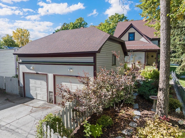 view of front of property with a garage, roof with shingles, and fence