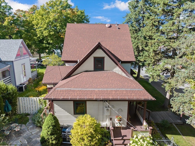 view of front facade with a shingled roof and fence