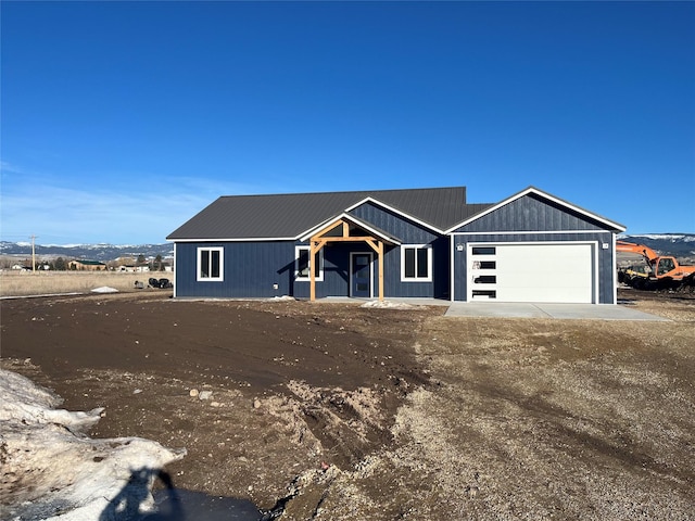 view of front of home featuring a garage, metal roof, and dirt driveway