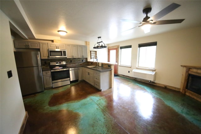 kitchen with stainless steel appliances, dark countertops, an AC wall unit, a sink, and a peninsula