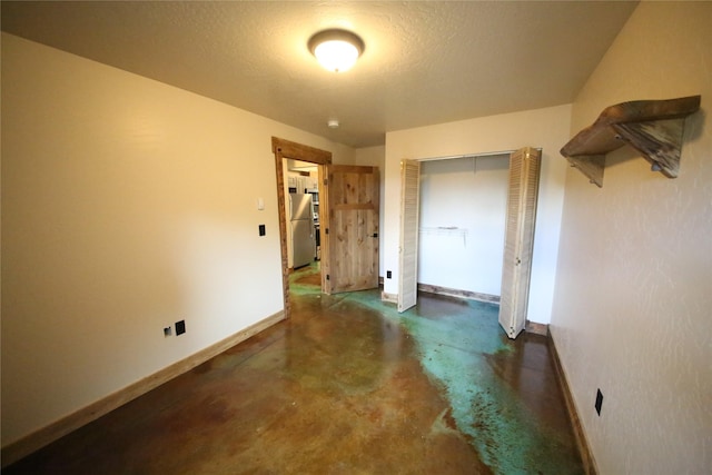 interior space featuring concrete floors, baseboards, and a textured ceiling