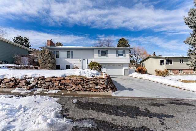 bi-level home with a garage, driveway, and a chimney